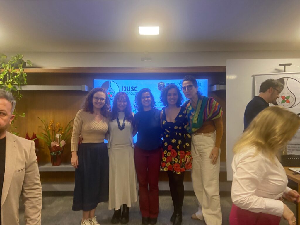 Participantes diante do painel com a marca do IJUSC
